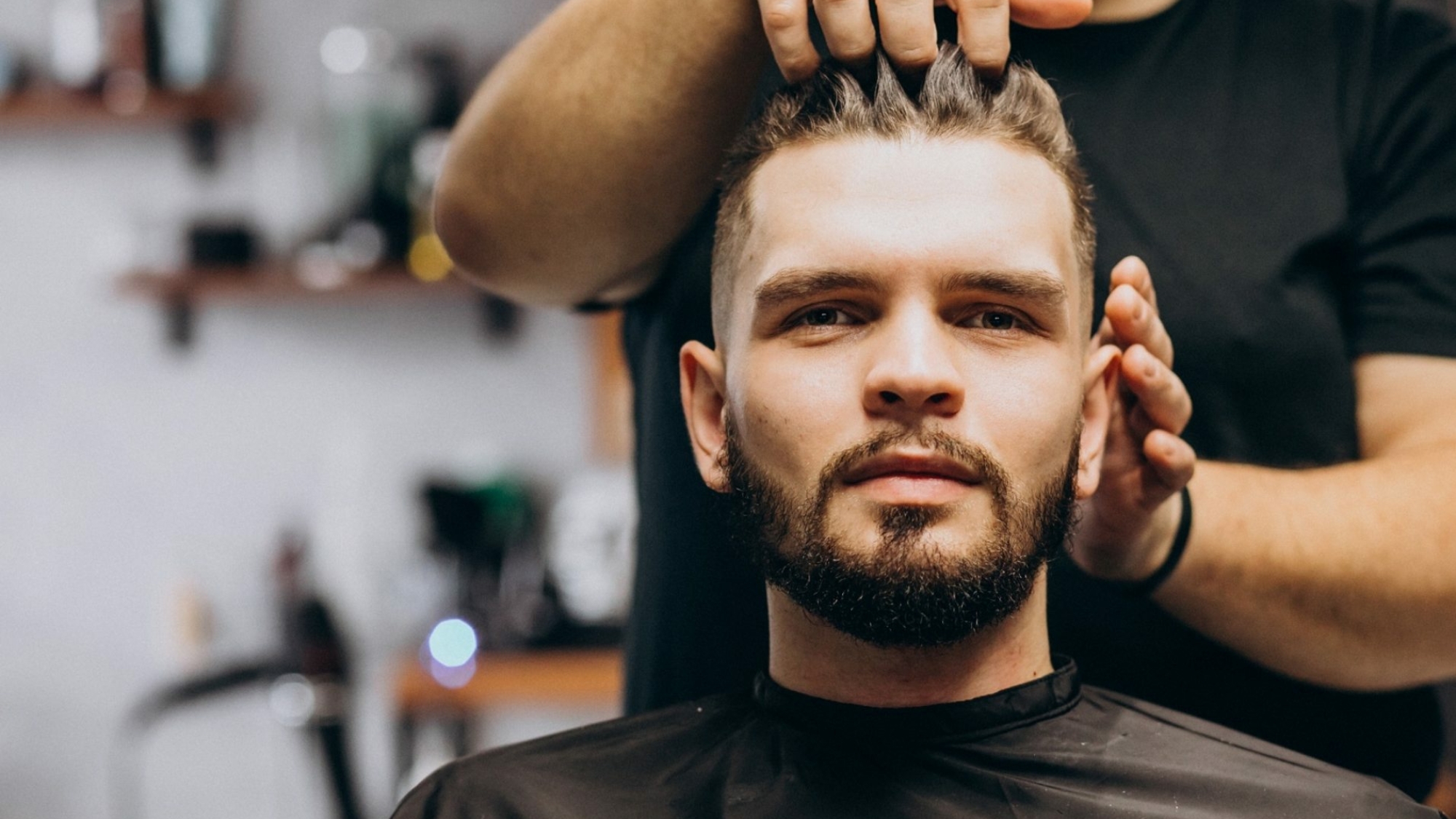 Hairdresser at a barber shop styling hair of a client