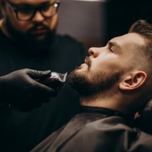 Handsome man cutting beard at a barber shop salon