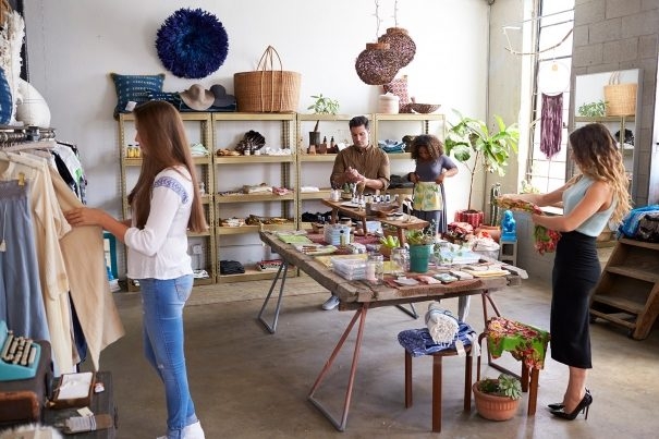 customers-and-staff-in-a-busy-clothes-shop-PKWD8LW-605x403